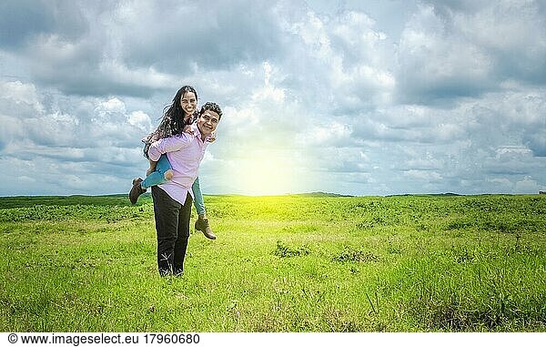 Happy couple in love in the field  happy man carrying his girlfriend in the field