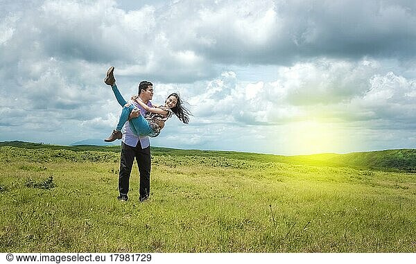 Happy couple in love in the field  happy man carrying his girlfriend in the field