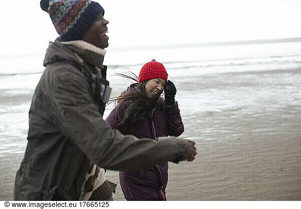 Happy couple in warm clothing on wet winter beach