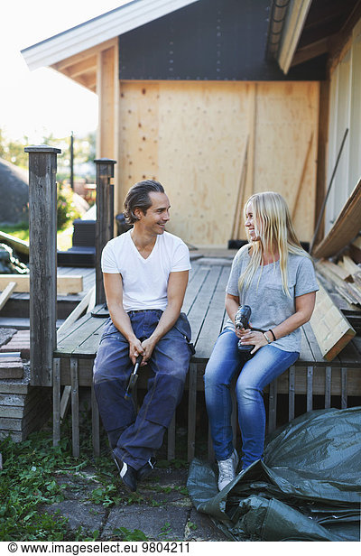 Happy couple looking at each other outside house during home improvement