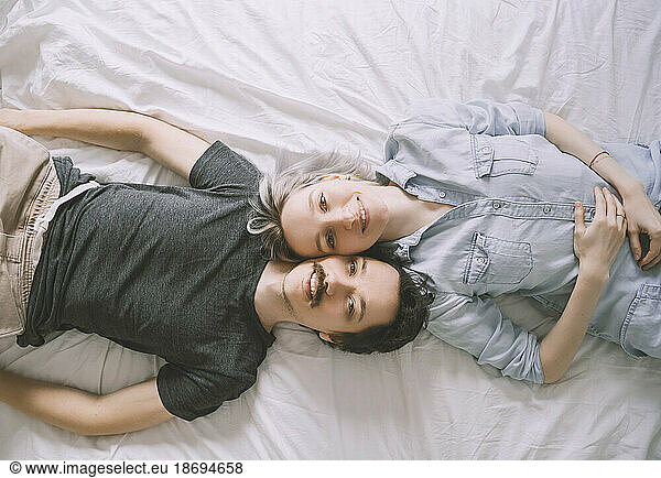 Happy couple lying on back together at home