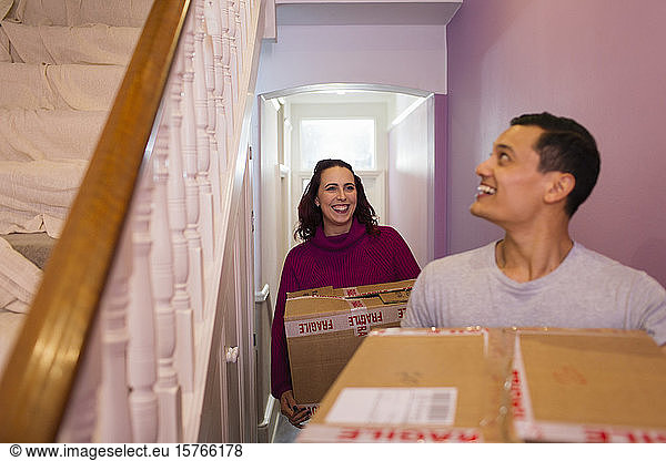 Happy couple moving into new house  carrying cardboard boxes in corridor