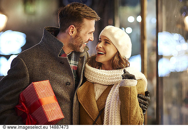 Happy couple on shopping tour at Christmas time looking at each other