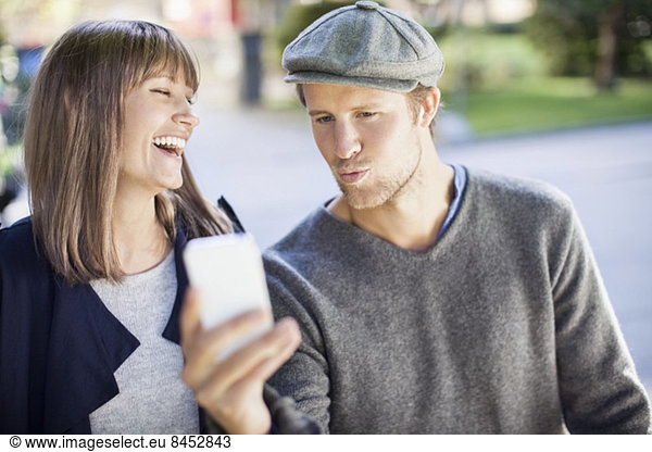Happy couple photographing themselves through mobile phone outdoors