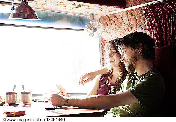 Happy couple playing cards while sitting in camper van