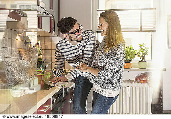 Happy couple reading newspaper in the kitchen  Munich  Germany