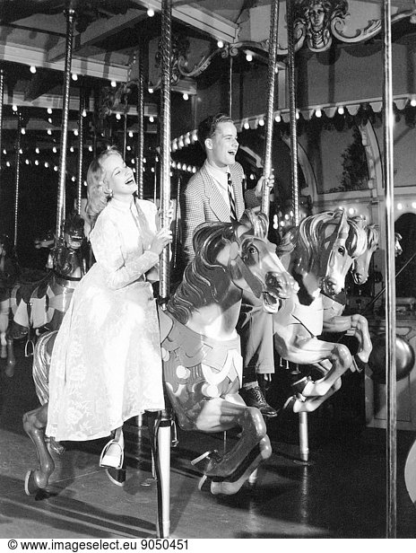 Happy couple riding horses on a carousel