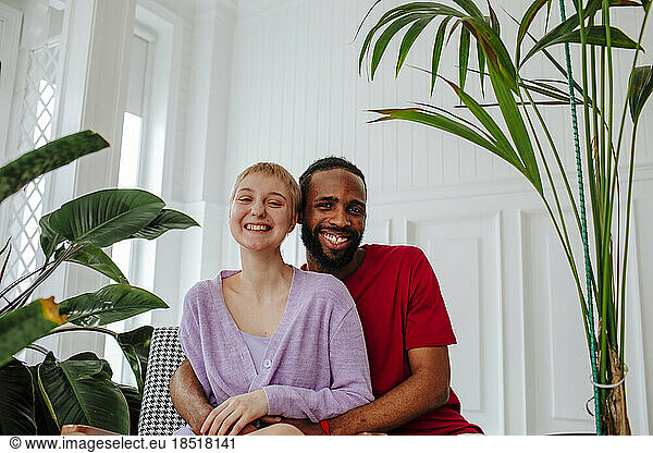 Happy couple sitting in front of white wall at home