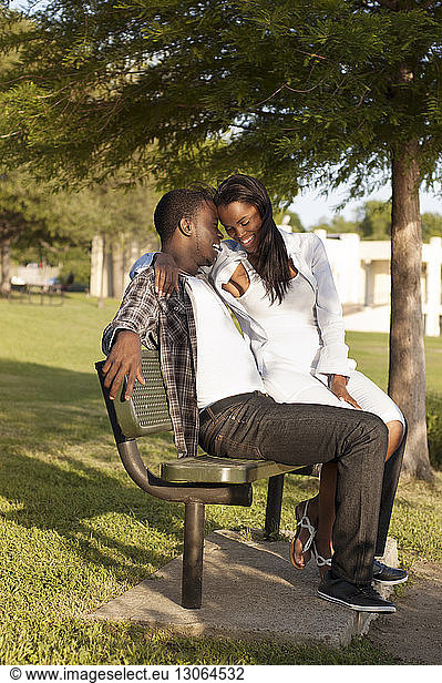Happy couple sitting on bench at park