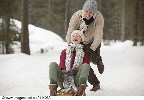 Happy couple sledding in snowy field
