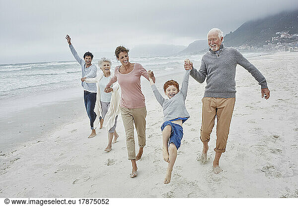 Happy couple spending quality time at the beach with son and grandparents