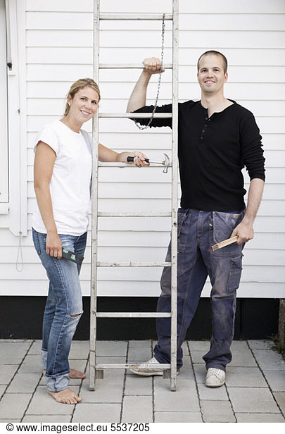 Happy couple standing by ladder