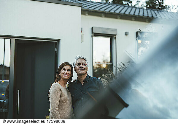 Happy couple standing together in front of house