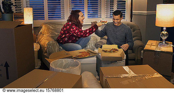 Happy couple taking a break from moving  eating pizza