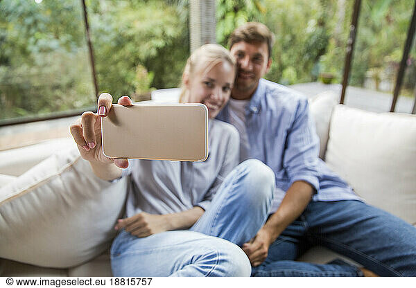 Happy couple taking selfie through smart phone at home