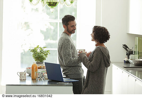 Happy couple talking and working in morning kitchen