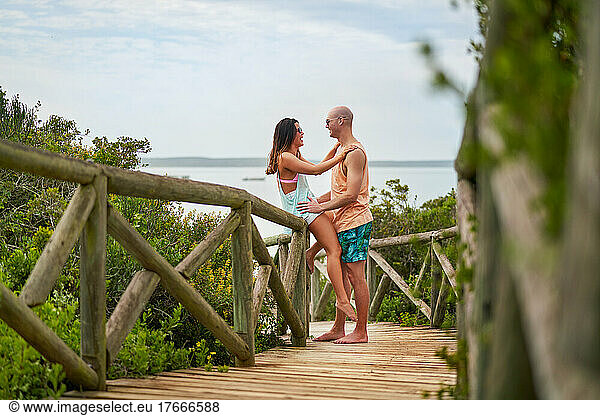 Happy couple talking face to face on beach boardwalk