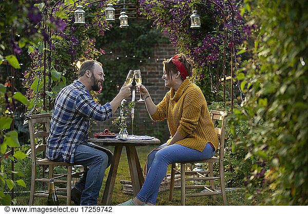 Happy couple toasting champagne in idyllic summer garden