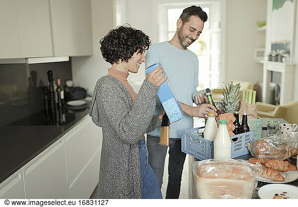 Happy couple unpacking grocery delivery at kitchen counter