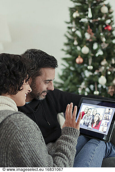 Happy couple video chatting with family on digital tablet at Christmas