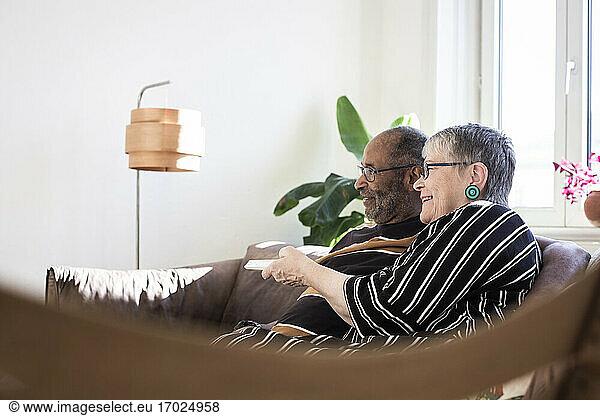 Happy couple watching television in living room