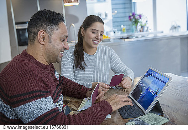 Happy couple with passports planning vacation at digital tablet