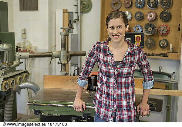 Happy craftswoman standing in woodshop