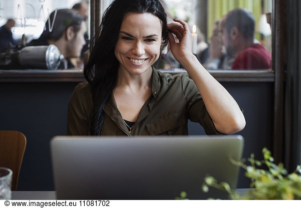 Happy creative businesswoman using laptop while sitting in office
