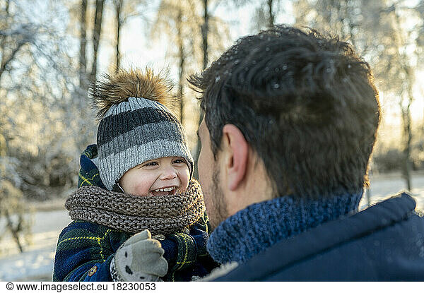 Happy cute boy with father wearing warm clothing in winter park