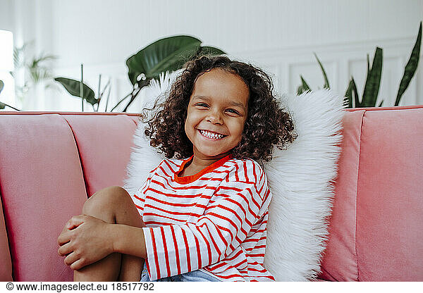 Happy cute girl sitting on sofa at home