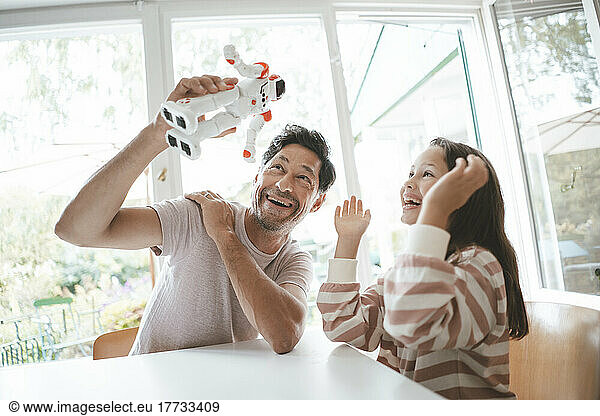 Happy daughter and father playing with toy robot at home