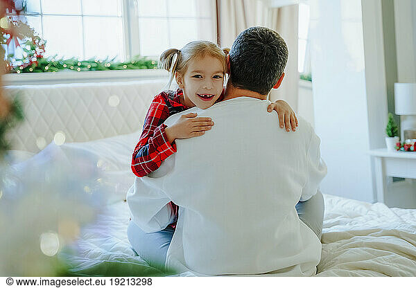Happy daughter hugging father on bed
