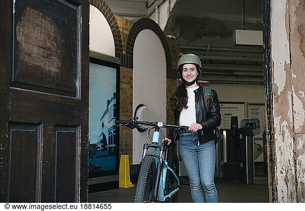 Happy delivery person standing with bicycle in doorway