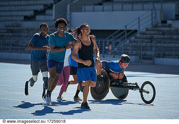 Happy diverse athletes running on sunny sports track