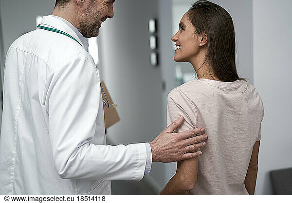 Happy doctor talking with patient in clinic