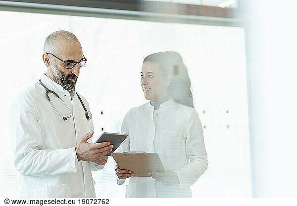 Happy doctor with colleague using tablet PC
