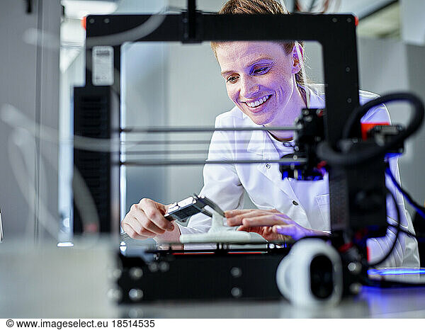 Happy engineer operating 3D printing machine in laboratory