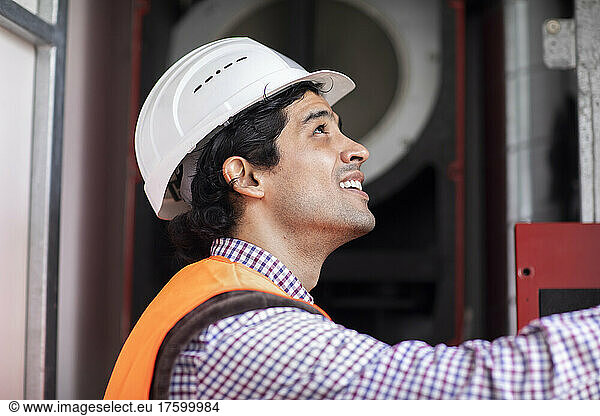 Happy engineer wearing hardhat looking up