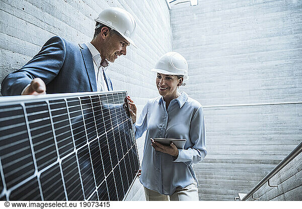 Happy engineers discussing over solar panel