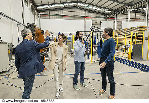 Happy engineers giving high-five to each other in robotic industry