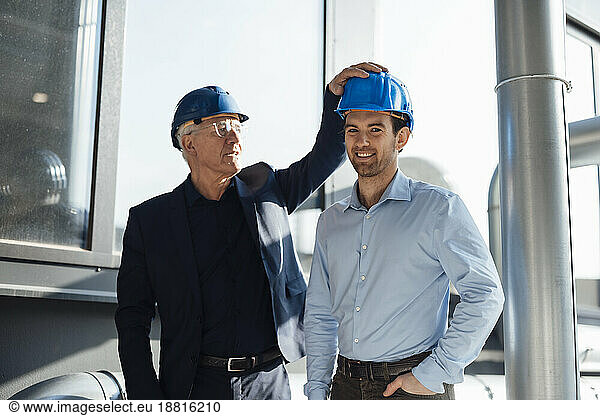 Happy engineers wearing hardhats standing at industry