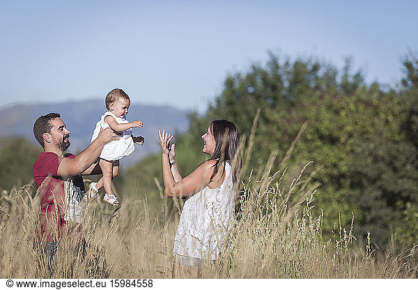 Happy family amidst plants in forest against sky on sunny day