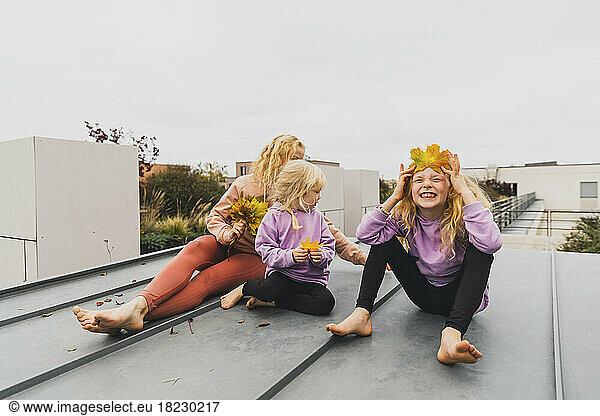 Happy family enjoying together with autumn leaves sitting at rooftop