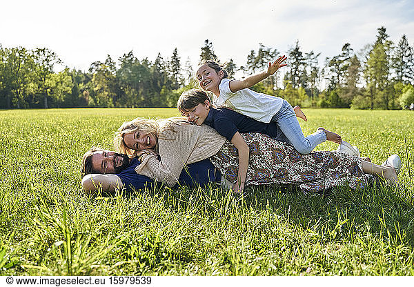 Happy family enjoying while lying on grass during sunny day