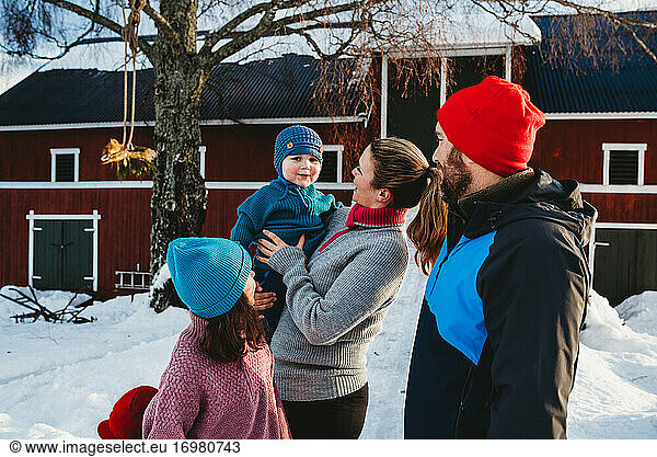 Happy family gathered by red Scandinavian bar in cold winter with snow