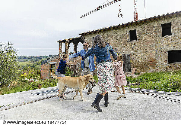 Happy family having fun with dog in front of house