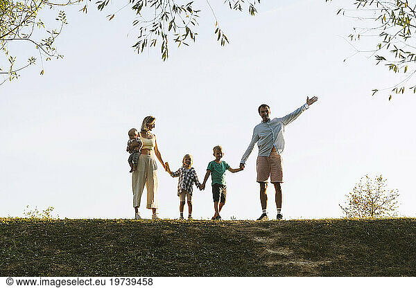 Happy family holding hands and standing in park