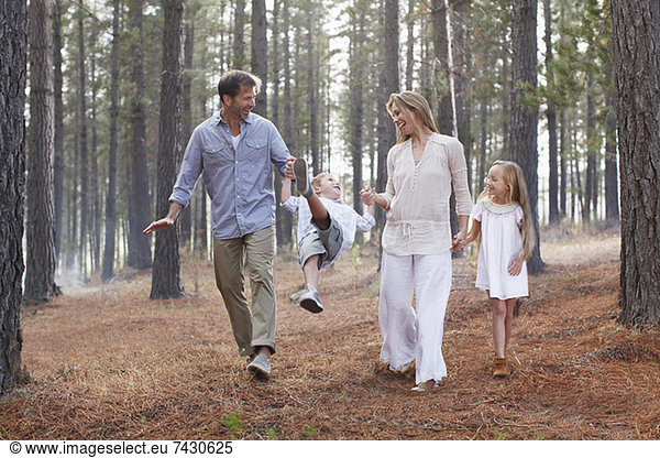 Happy family holding hands and walking in woods