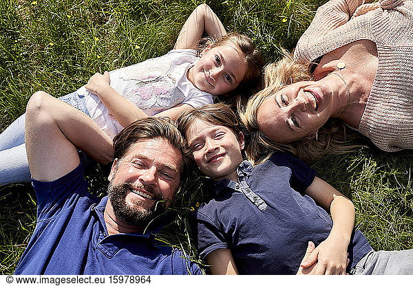 Happy family lying on grass during sunny day