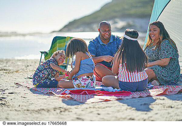 Happy family on picnic blanket at sunny beach